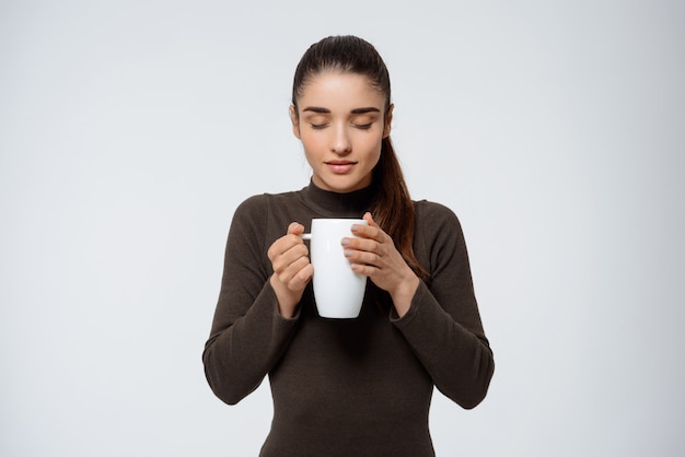 Tedere glimlachende vrouw die heerlijke koffie ruikt