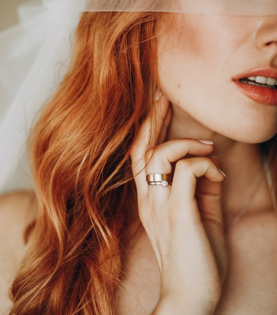Tedere lippen en huid van charmante bruid met rood krullend haar