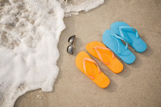 Teenslippers, zonnebril en zeester in zand