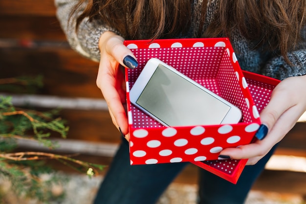 Telefoon als kerstcadeau in rode kerstdoos in handen van mooi meisje.