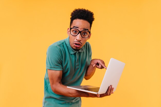 Teleurgesteld Afrikaanse student poseren met laptop. Geschokt zwarte mannelijke freelancer bedrijf computer.