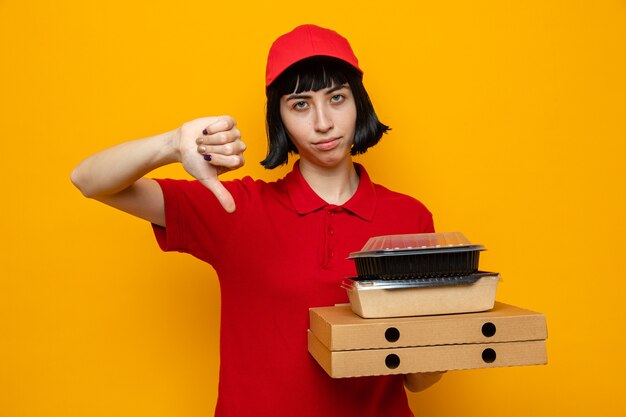 Teleurgesteld jong kaukasisch bezorgmeisje met voedselcontainers met verpakking op pizzadozen