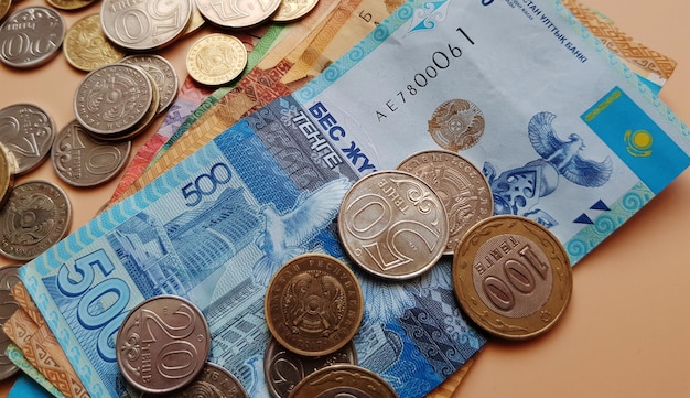 Tenge. geld. kazachse munten en biljetten liggen op de beige tafel close-up.
