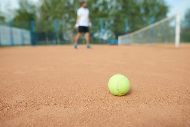 Tennisbal en man in de tennisbaan