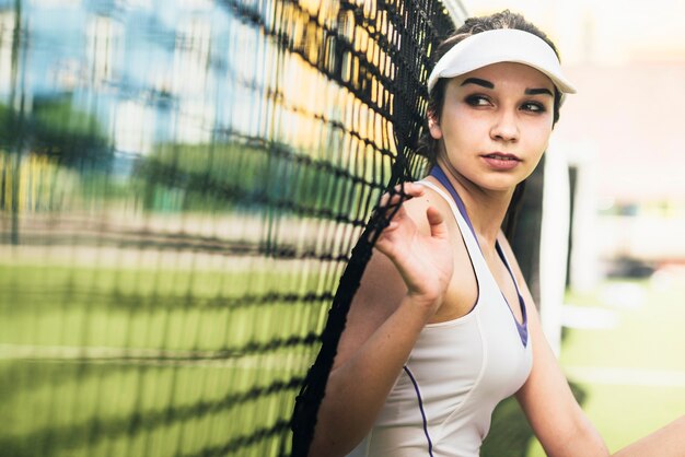 Tennisspeler die op netto leunt