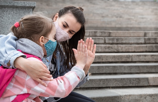 Terug naar school. Kinderen met een coronavirus-pandemie gaan met maskers naar school. Vriendschappelijke betrekkingen met moeder. Kinderopvoeding.