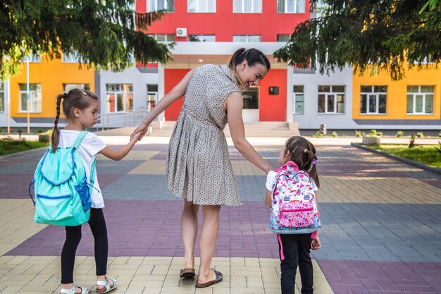 Terug naar school onderwijsconcept met meisjeskinderen, elementaire studenten, die rugzakken dragen die naar klasse gaan