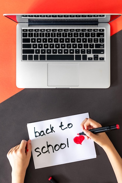 Gratis foto terug naar school schrijft de hand van het kind in een papier op een gekleurde achtergrond