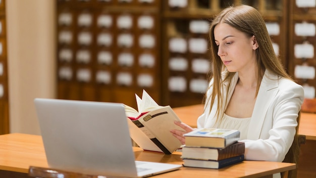 Gratis foto terug naar schoolconcept met vrouw die in bibliotheek bestudeert