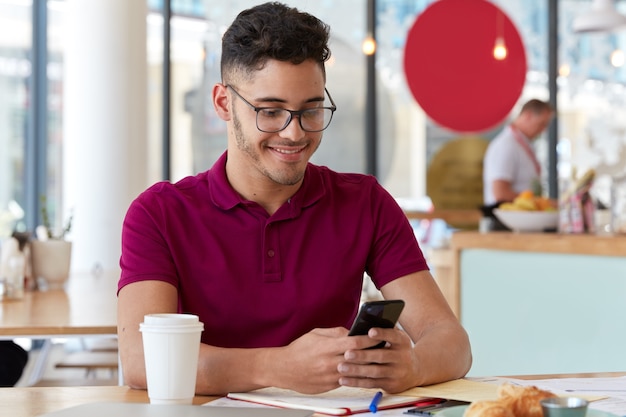 Tevreden freelancer werkt online, is mobiel, stuurt sms-berichten op sociale netwerken, zit in een restaurant. student wisselt notificaties uit met groepsgenoot, bereidt zich voor op seminar, schrijft notities