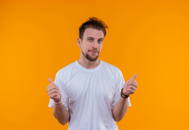 Tevreden jonge kerel die wit t-shirt draagt zijn duimen omhoog op geïsoleerde oranje achtergrond