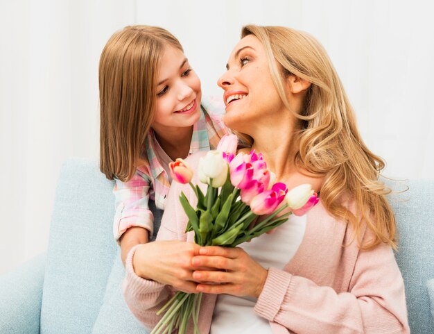 Tevreden mama met tulpen die dochter bekijken