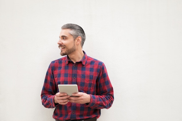 Tevreden mens die met digitale tablet opzij kijkt