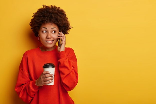 Tevreden vrouw met een donkere huid praat nonchalant en drinkt aromatische dranken