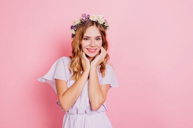 Tevreden vrouw met kort golvend haar dat haar gezicht met glimlach aanraakt