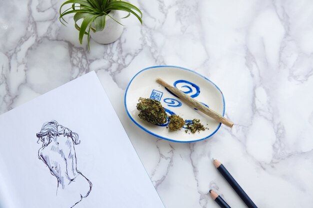 THC CBD Marihuana joint en bloemen op asbak met naaktillustratie op tekenblok