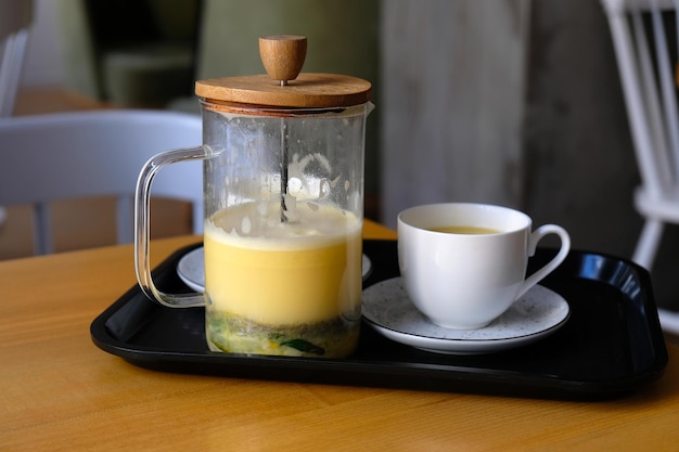 Thee met citrus, takjes rozemarijn en boter. tibetaanse thee met olie in een glazen theepot en een kopje op een dienblad.