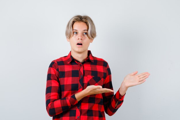 Tiener blonde man in casual shirt wegkijken en geschokt kijken, vooraanzicht.