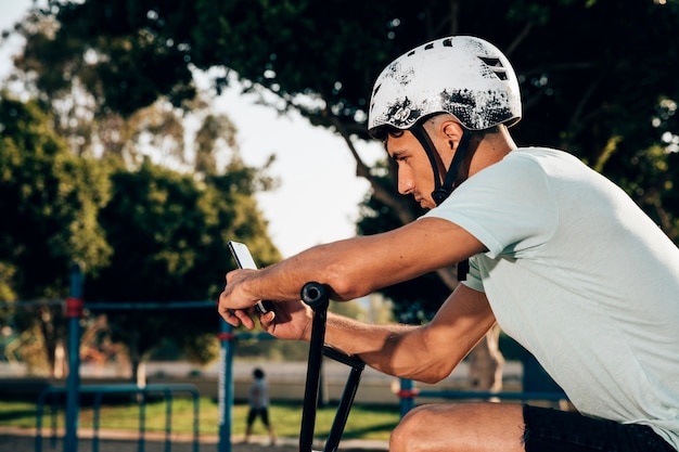 Tiener bmxruiter die de telefoon bekijkt