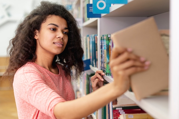 Tiener die boek plaatst op boekenrek