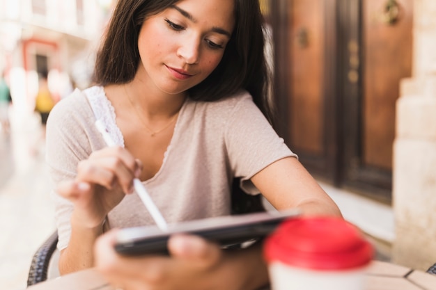 Tiener die naald op digitale tablet gebruiken bij openluchtcaf�