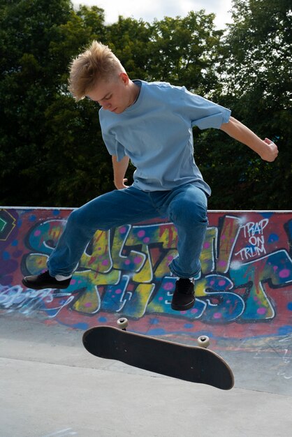 Tiener doet truc op skateboard zijaanzicht