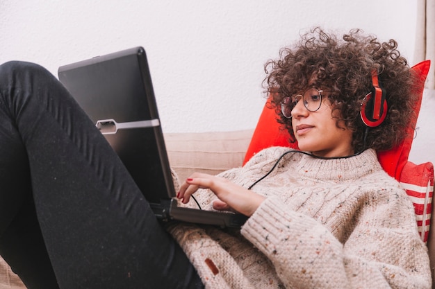 Tiener in hoofdtelefoons die laptop met behulp van