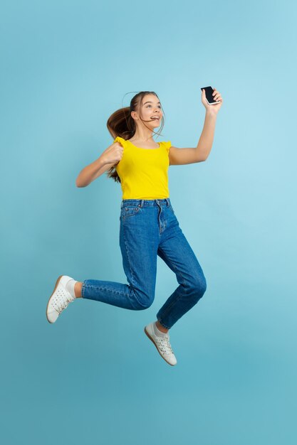 Tiener meisje hoog springen met smartphone