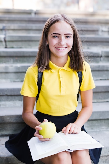 Gratis foto tiener met boek en appel