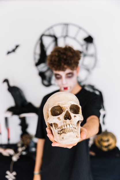 Gratis foto tiener met halloween-schedel van de zombie de onverbiddelijke holding