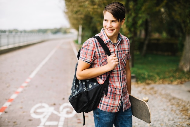 Tiener met skateboard en rugzak