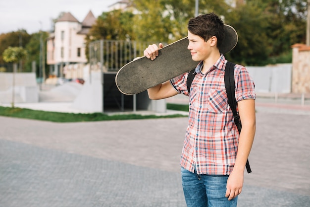 Gratis foto tiener met skateboard wegkijken