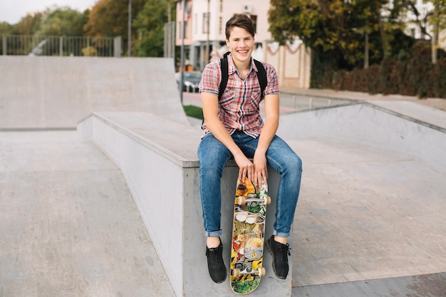 Tiener met skateboard zittend op de rand