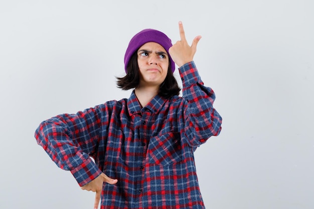 Gratis foto tiener vrouw in geruit hemd en muts gebaren geïsoleerd