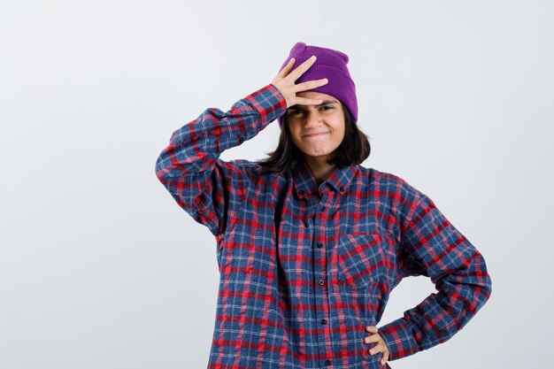 Tiener vrouw in geruit overhemd paars met een hand op het hoofd en een andere hand op de heup