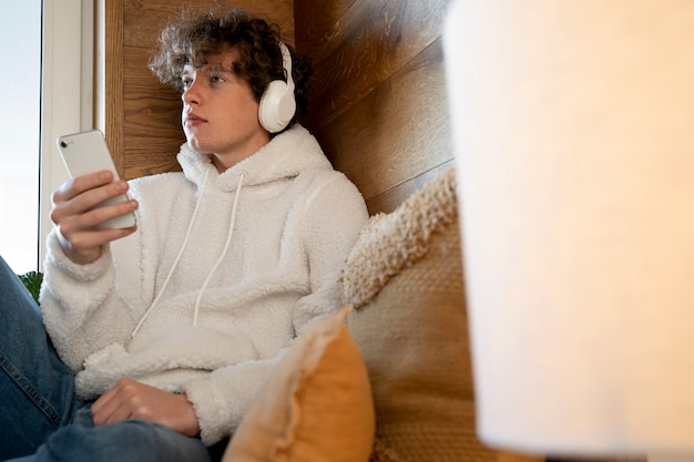 Tiener zit in zijn bed en luistert naar muziek met zijn smartphone