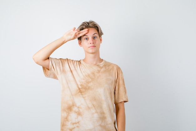Tienerjongen die een groetgebaar in t-shirt toont en er zelfverzekerd uitziet, vooraanzicht.