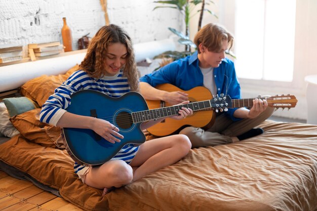 Gratis foto tienerjongen en meisje die muziek opnemen met gitaar in hun thuisstudio