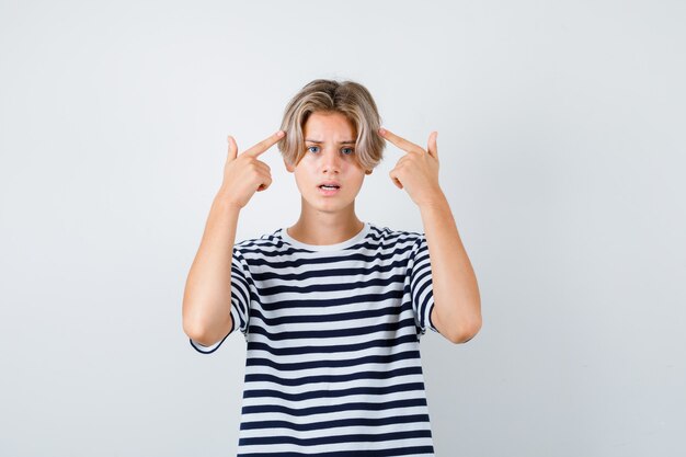 Tienerjongen wijzend naar zijn hoofd in t-shirt en verward kijken. vooraanzicht.