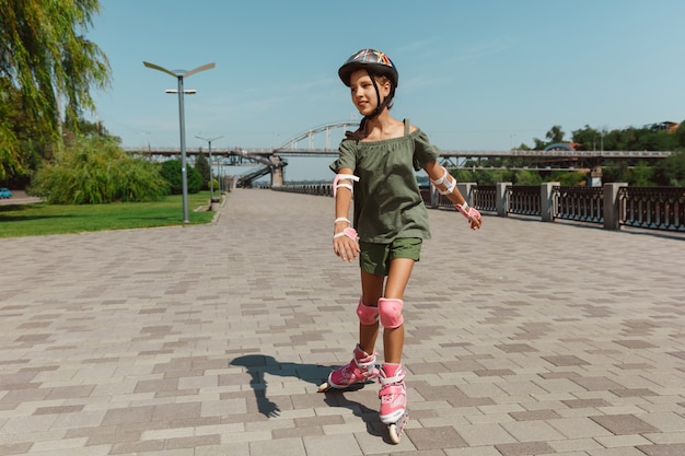 Gratis foto tienermeisje in een helm leert buiten op rolschaatsen te rijden