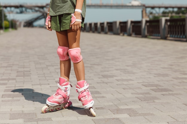 Tienermeisje in een helm leert rijden op rolschaatsen met een balans of skaten en draaien in de straat van de stad op zonnige zomerdag