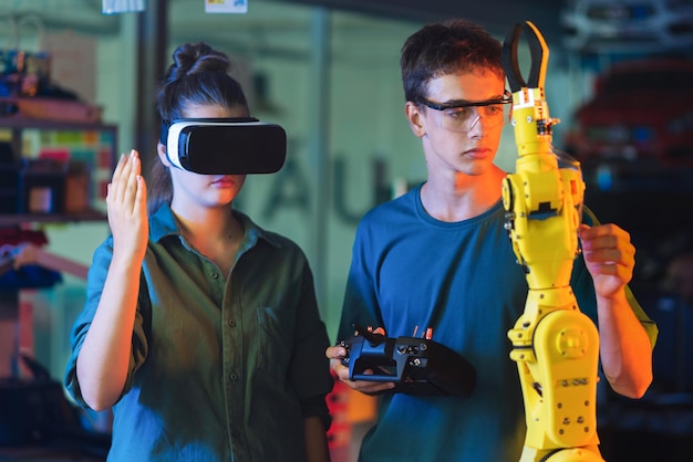 Tieners doen experimenten in robotica in een laboratorium Jongen met een beschermende bril die een robot aanraakt