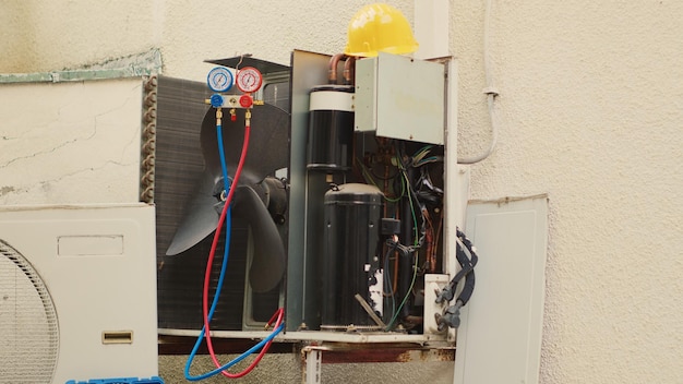 Gratis foto tilt-up schot van buiten dienst condenser eenheid met bescherming deksel verwijderd in de behoefte aan reparatie, met beschadigde elektrische interne delen. buiten hvac-systeem niet meer werken, klaar om te worden gerepareerd