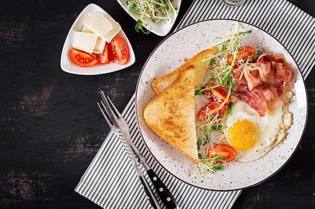 toast, ei, bacon en tomaten en microgreensalade.