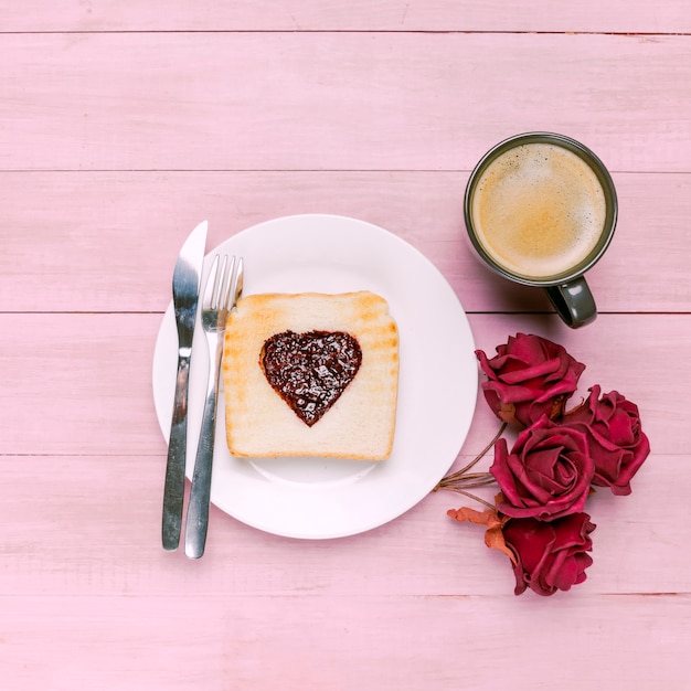 Toast met jam in hartvorm met rozen en koffie