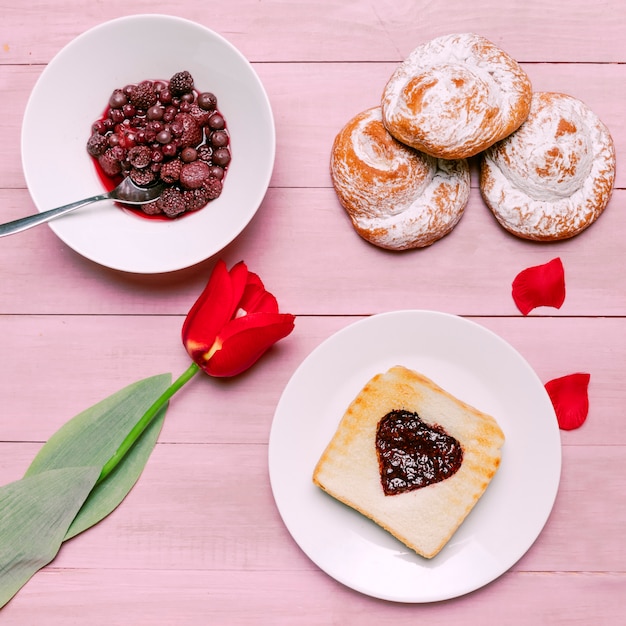 Gratis foto toast met jam in hartvorm met tulp en bessen