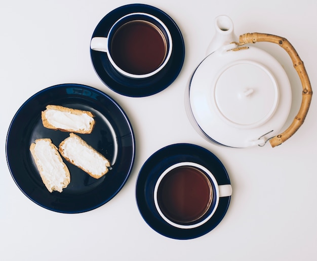 Toast met kaas; koffiekopje en theepot op witte achtergrond