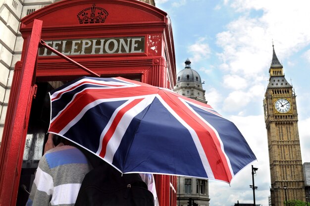 Toerist met British paraplu in telefooncel in Londen