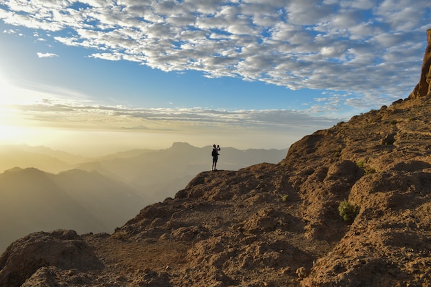 Gratis foto toerist op de top van een rotsachtige berg in gran canaria, spanje