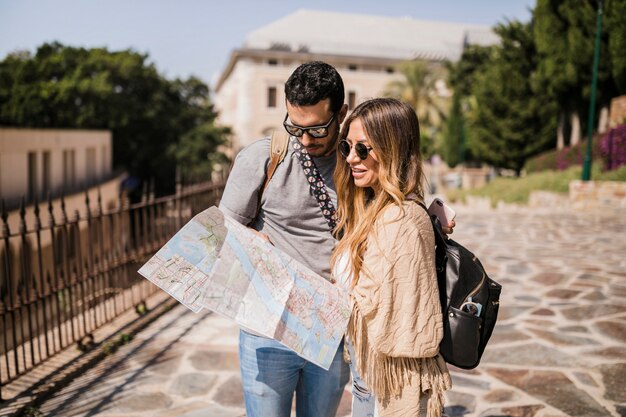 Toeristen jong paar die zich op straat bevinden die kaart bekijken